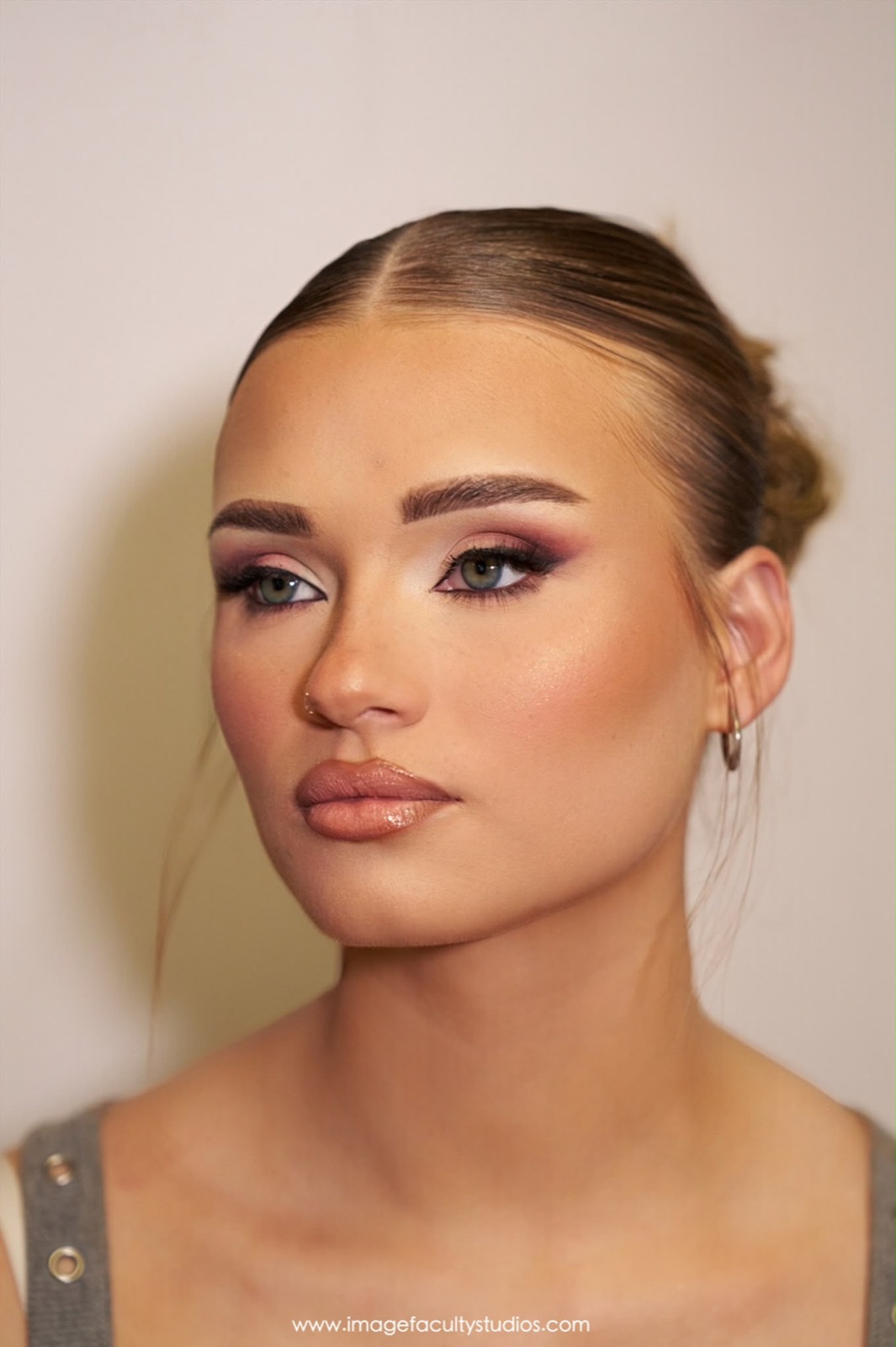Studio beauty portrait with a sleek bun and rose-toned glam