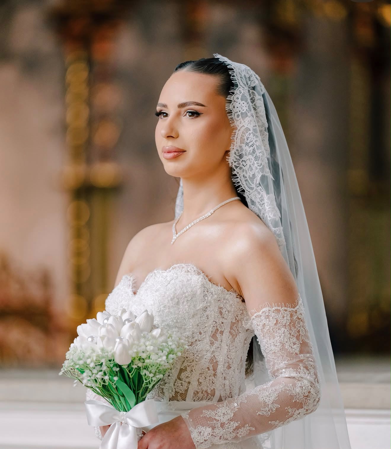 Bride in lace with a cathedral veil holding a white tulip bouquet